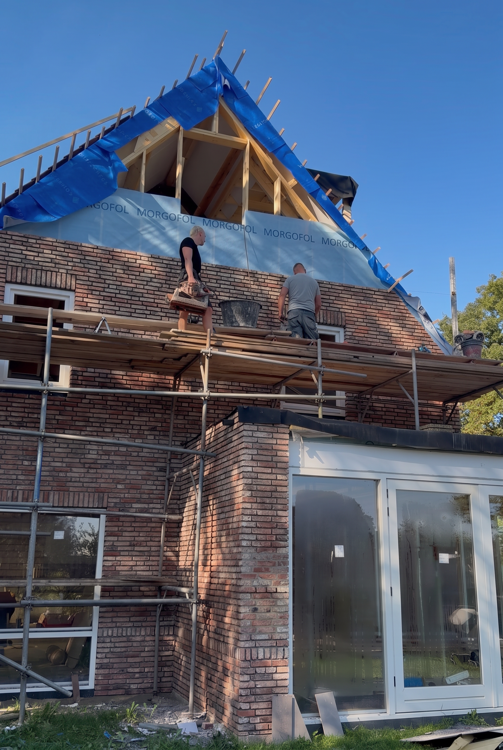 Twee vakmensen aan het werk tussen de dakspanten