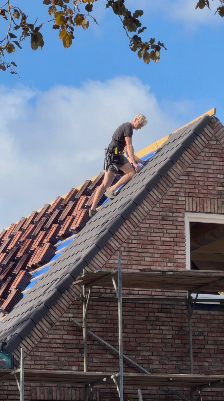 Vakman legt dakpannen op een schuin dak