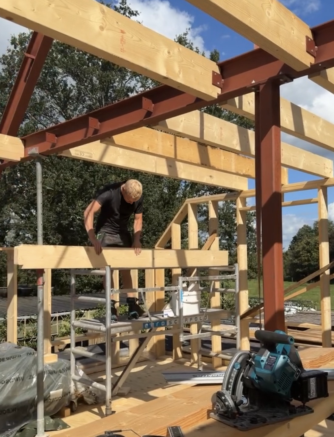 Vakman plaatst een houten balk in een constructie van hout en staal
