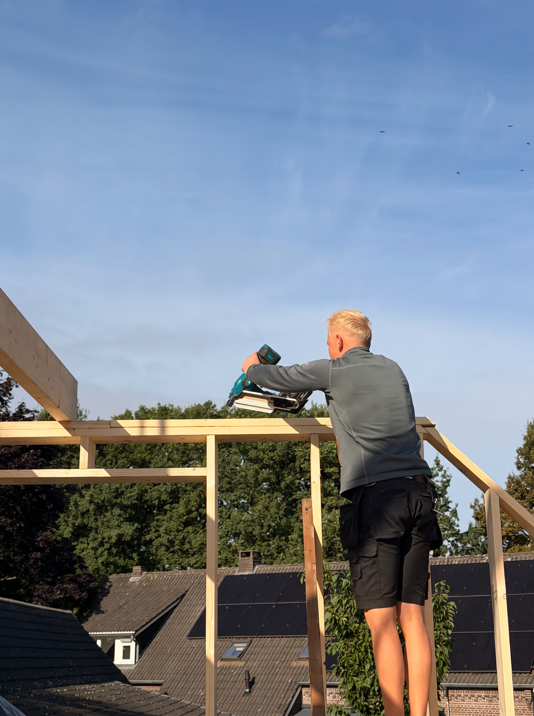 Vakman timmert het houten skelet van een opbouw